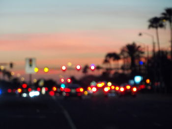 Defocused image of illuminated road against sky at night