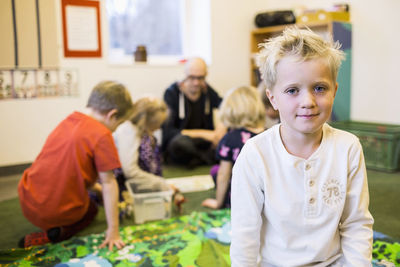 Portrait of boy with teacher and classmates in background at kindergarten