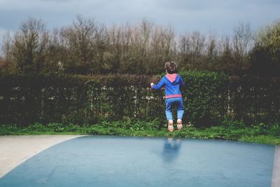 Rear view of boy jumping on trampoline
