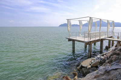 Gazebo on rocks by sea against sky