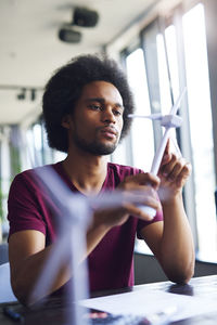 Young man looking at windmill model in office