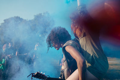 Man piggyback amidst blue powder paint while celebrating holi