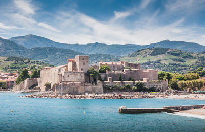 Buildings in sea against cloudy sky