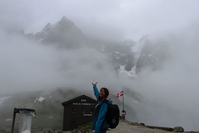 Portrait of woman standing on mountain against cloudy sky during foggy weather