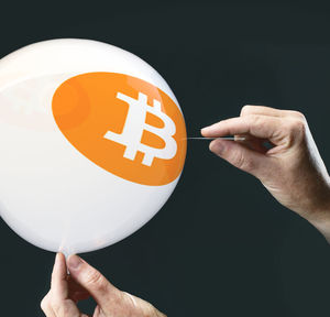 Cropped hand of man holding straight pin by balloon against black background