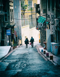 Rear view of people walking on street amidst buildings in city