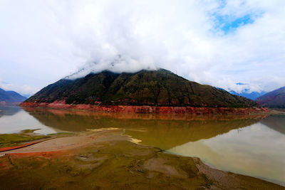 Scenic view of lake by mountains against sky