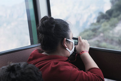 Rear view of woman looking through window