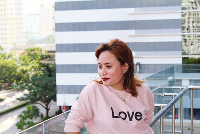 Portrait of woman standing against railing