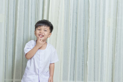 Portrait of smiling girl standing against curtain