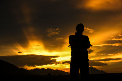 Rear view of silhouette man standing against sky during sunset