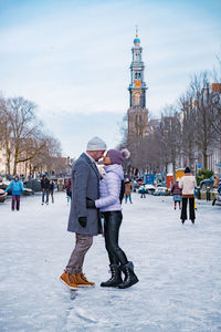 People walking in snow against built structure during winter