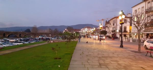 People on footpath amidst buildings in city at night