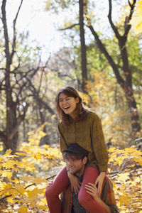 Young woman playfully sitting on her boyfriend's shoulders