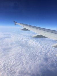 Airplane flying over clouds against blue sky