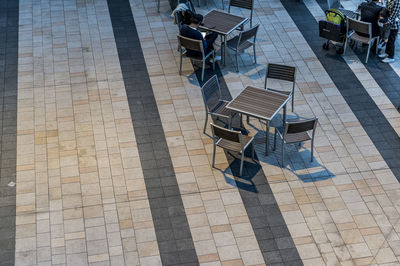 High angle view of empty chairs and tables at sidewalk cafe against buildings