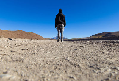 Rear view of man standing on desert against sky