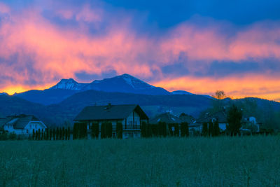 Houses by mountains against sky at sunset