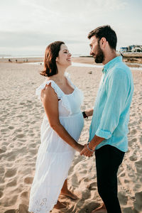 Smiling couple holding hands embracing at beach