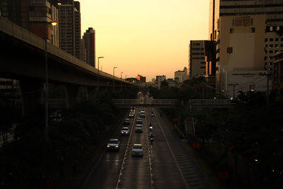 Cars on road in city against sky during sunset