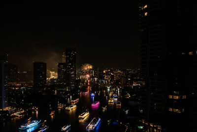 Illuminated buildings in city against sky at night