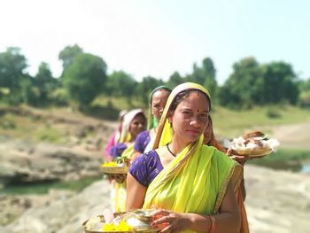 Young woman sitting on land against sky