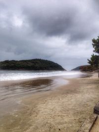 Scenic view of beach against cloudy sky