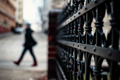 Close up of metallic fence against person walking on street