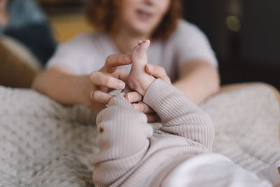 Mum making baby massage, mother massaging infant bare foot, preventive massage for newborn