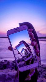 Close-up of mobile phone on beach against sky during sunset