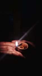 Close-up of hand holding lit candle