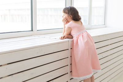 Side view of girl looking through window