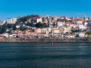 Scenic view of sea by town against clear blue sky