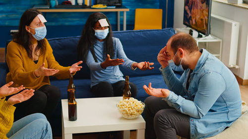 Friends sitting by food and drink on table at home