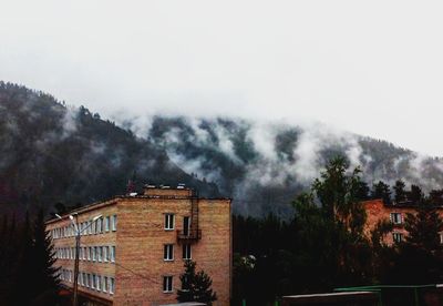 Houses on mountain against cloudy sky