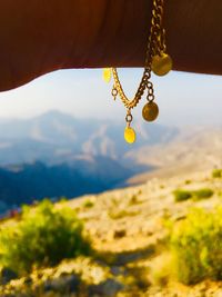 Close-up of hanging from hand  against mountain