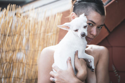 Adorable portrait of strong woman cuddling dog close to face on balcon