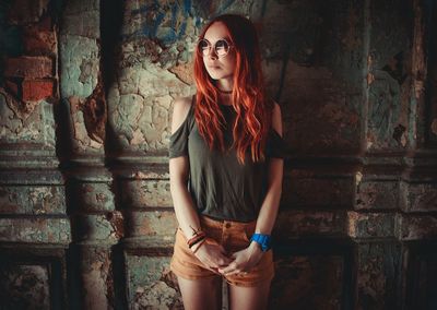Young woman with long hair standing against wall