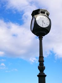 Low angle view of clock against cloudy sky