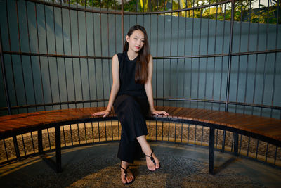 Portrait of young woman smiling while standing against railing