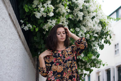 Beautiful woman standing against plants in city