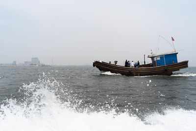 Fishing boat sailing in sea against clear sky