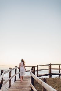 Rear view of woman standing on pier