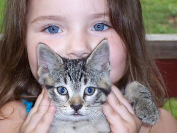 Close-up portrait of cute girl holding kitten