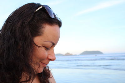 Close-up of woman smiling at beach against sky