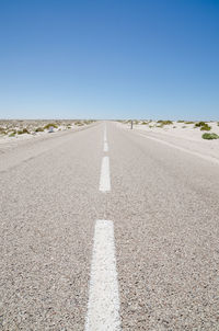 Empty road through sahara desert against clear blue sky, western sahara, africa