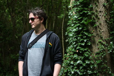 Young man wearing sunglasses standing in forest