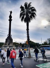 People on city street against cloudy sky