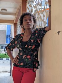 Portrait of young woman standing against wall