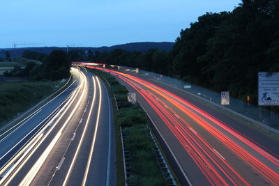 Light trails on streets against sky at dusk